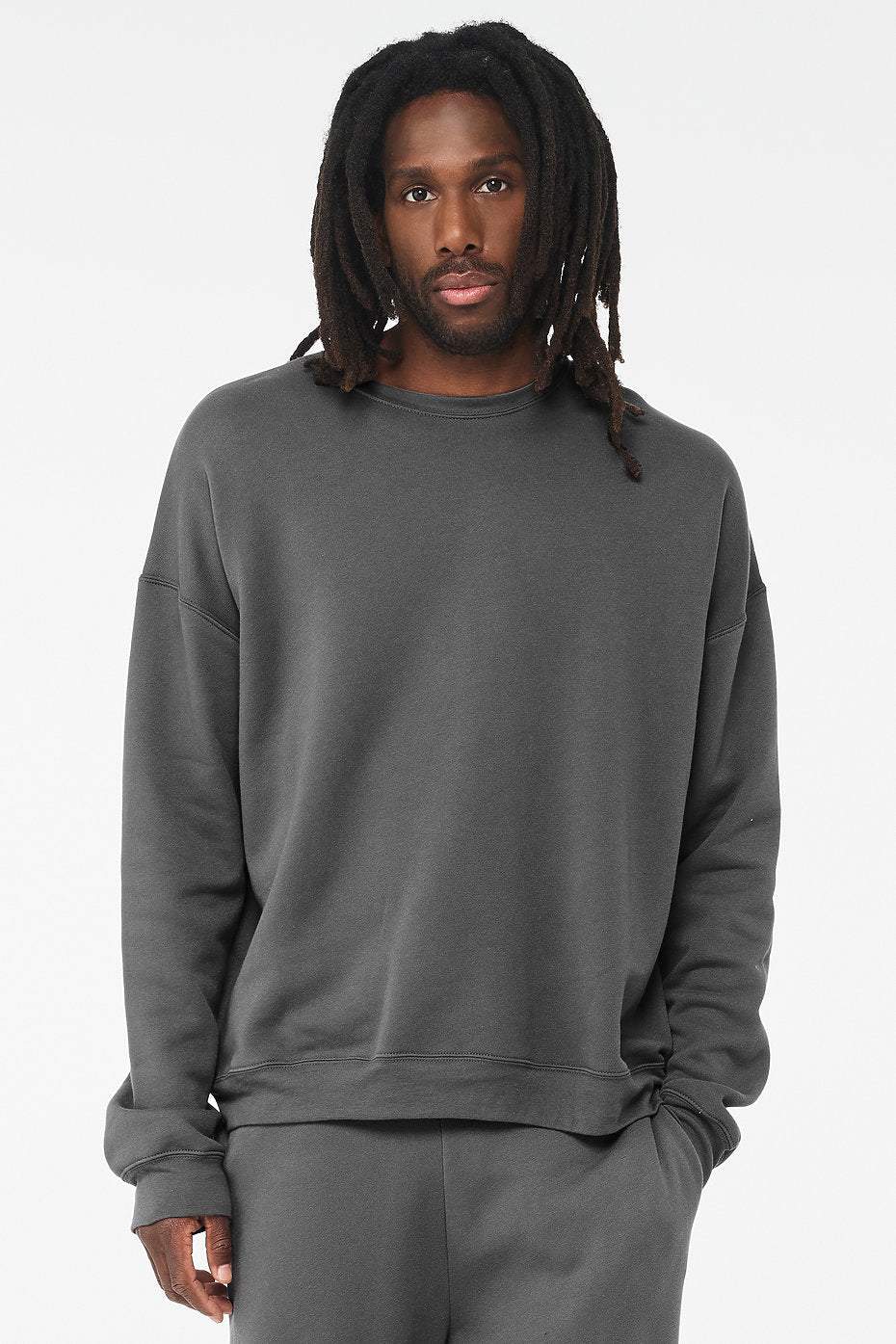 Unisex sponge fleece drop shoulder sweatshirt in dark gray with ribbed cuffs and waistband worn by male model